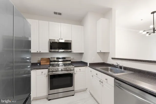 a kitchen with granite countertop white cabinets and stainless steel appliances
