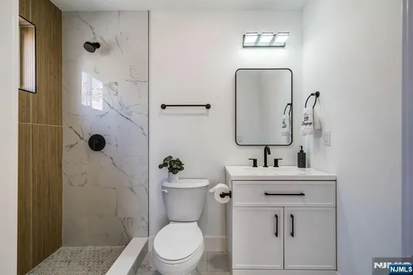 a bathroom with a sink a toilet a mirror and shower