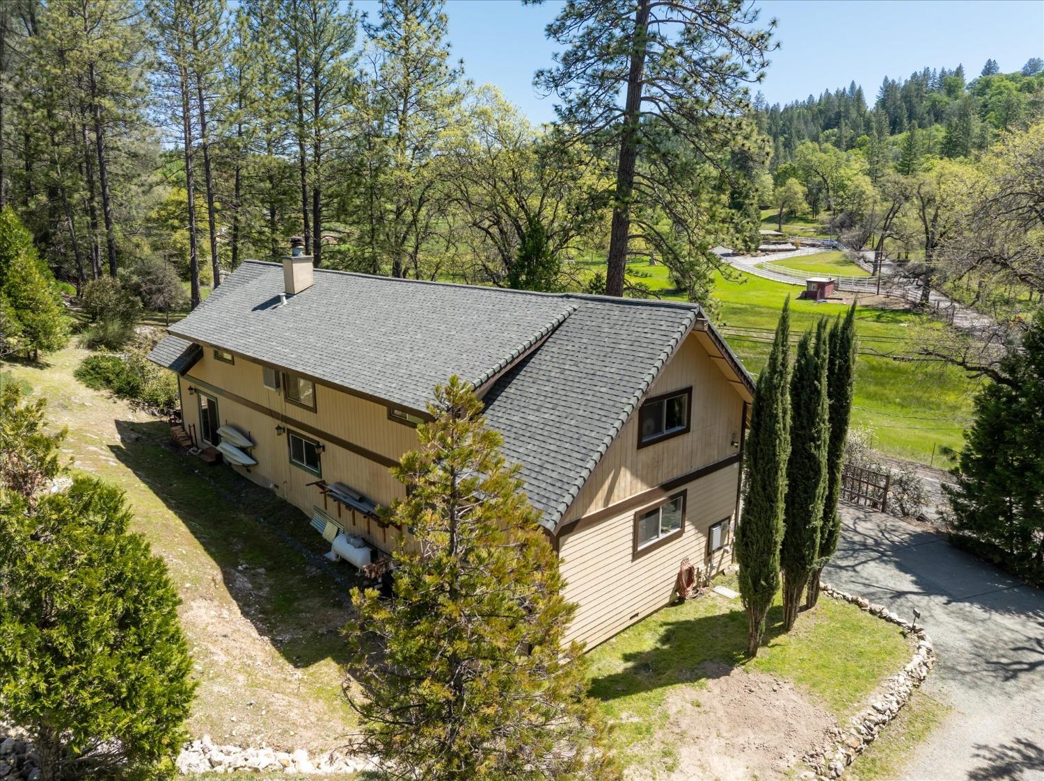 an aerial view of a house with swimming pool and trees