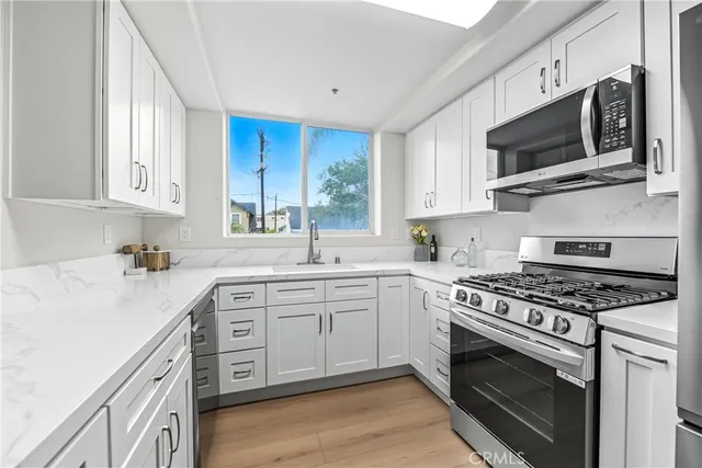 a kitchen with stainless steel appliances granite countertop a sink a stove a microwave and wooden cabinets