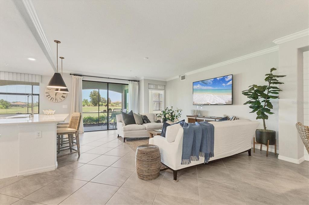 18113 Gawthrop Drive, Unit 101 Lakewood Ranch, FL 34211 - Photo 8 of 73 a living room with furniture a chandelier and a flat screen tv