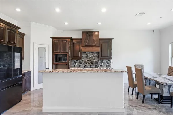 a kitchen with stainless steel appliances kitchen island granite countertop a refrigerator and a stove top oven
