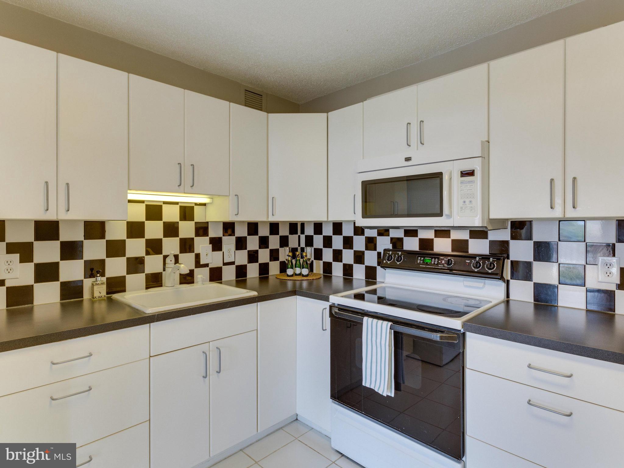 6800 Fleetwood Road, Unit 711 McLean, VA 22101 - Photo 4 of 27 a kitchen with granite countertop white cabinets and black appliances