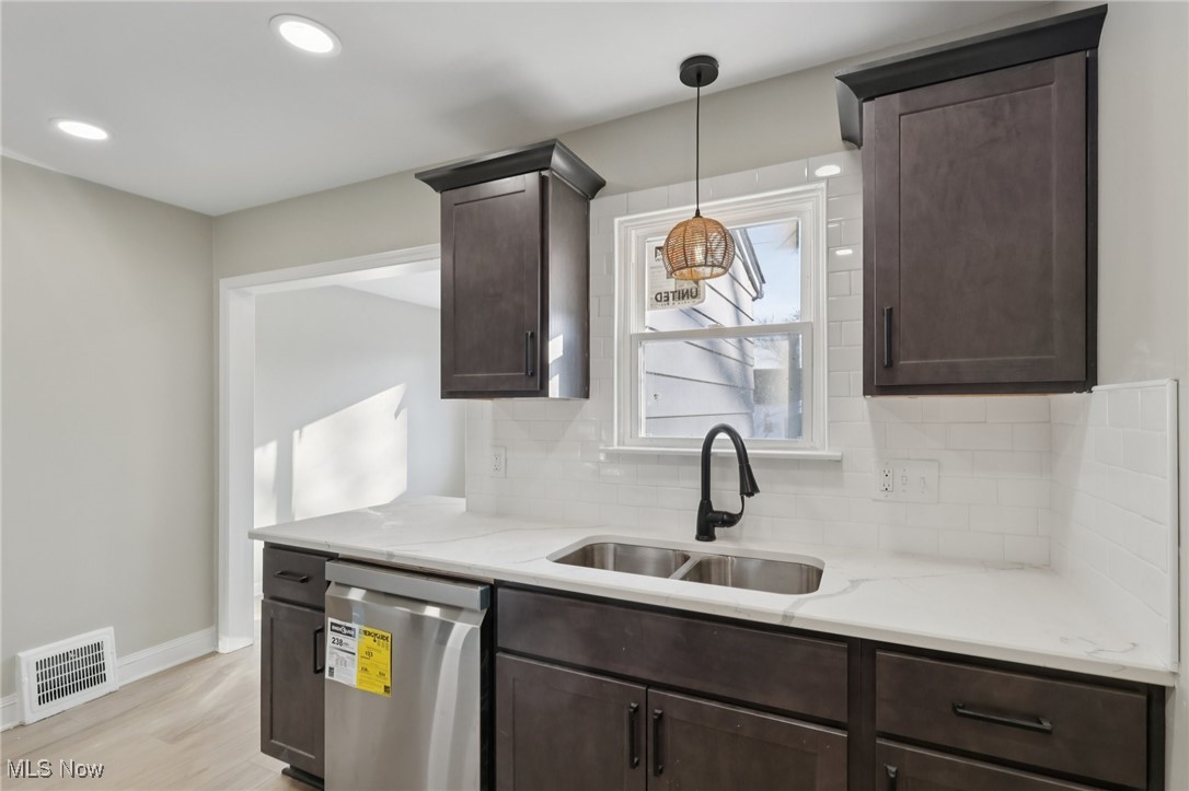 21316 Watson Road Maple Heights, OH 44137 - Photo 10 of 23 Kitchen featuring decorative backsplash, dark brown cabinets, stainless steel dishwasher, light stone counters, and recessed lighting