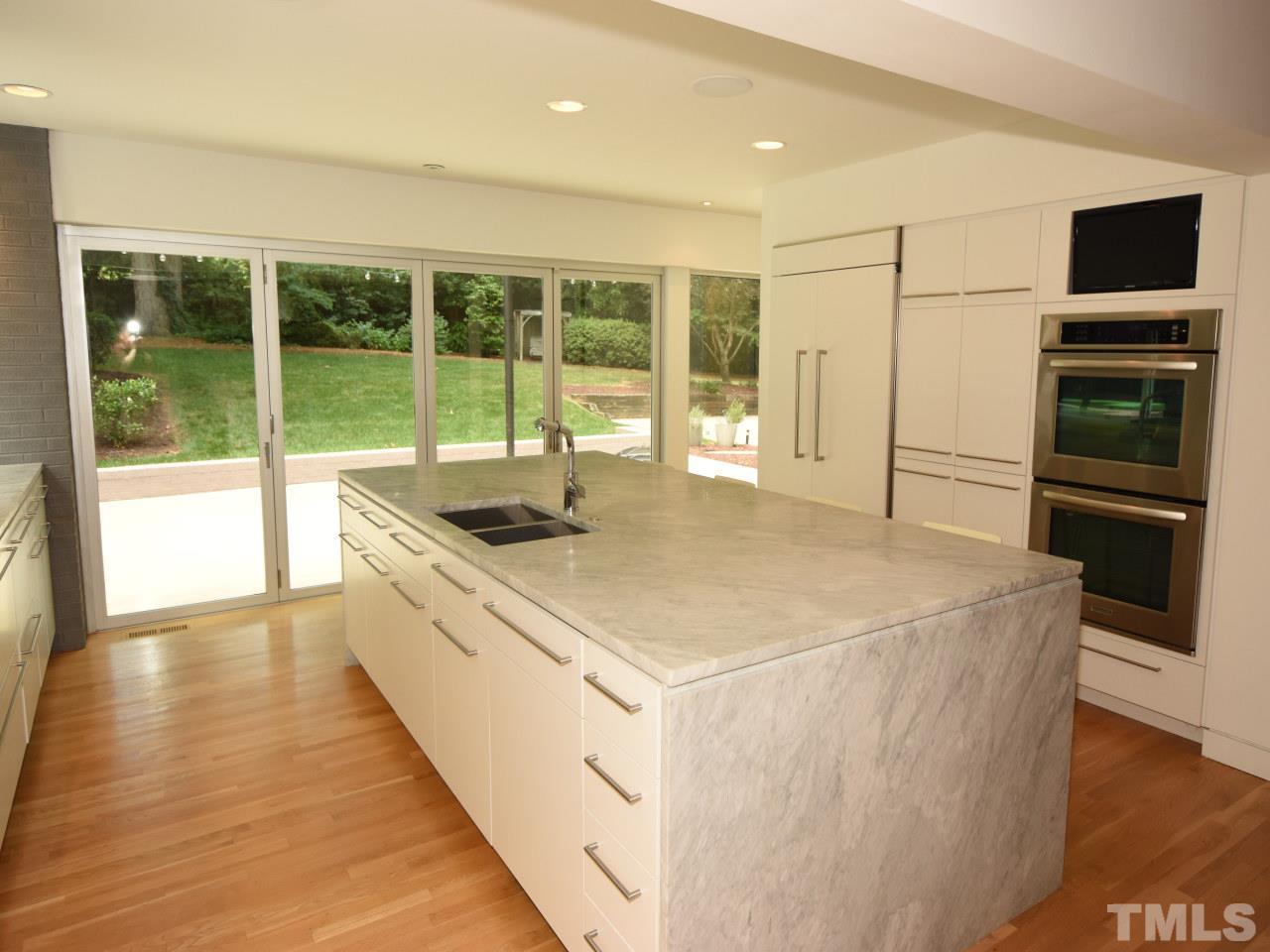 2109 St James Road Raleigh, NC 27607 - Photo 5 of 25 a large white kitchen with kitchen island a large window and stainless steel appliances