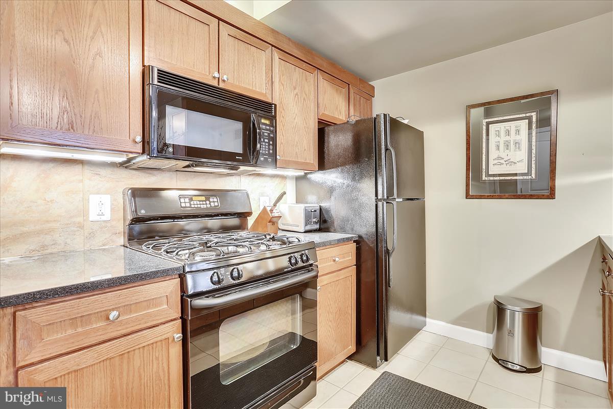 616 E Street Northwest, Unit 1207 Washington, DC 20004 - Photo 2 of 25 a kitchen with stainless steel appliances granite countertop a stove microwave and refrigerator