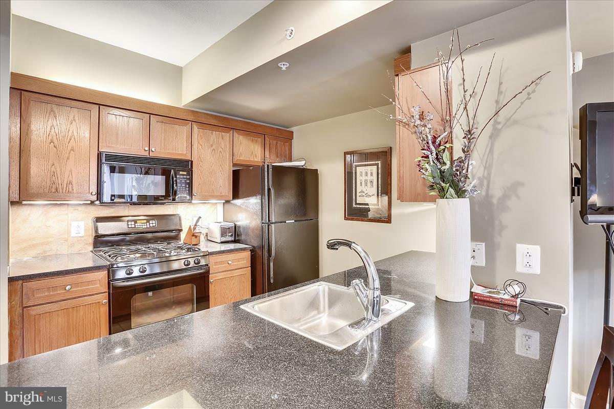 616 E Street Northwest, Unit 1207 Washington, DC 20004 - Photo 4 of 25 a kitchen with stainless steel appliances granite countertop a sink stove and refrigerator