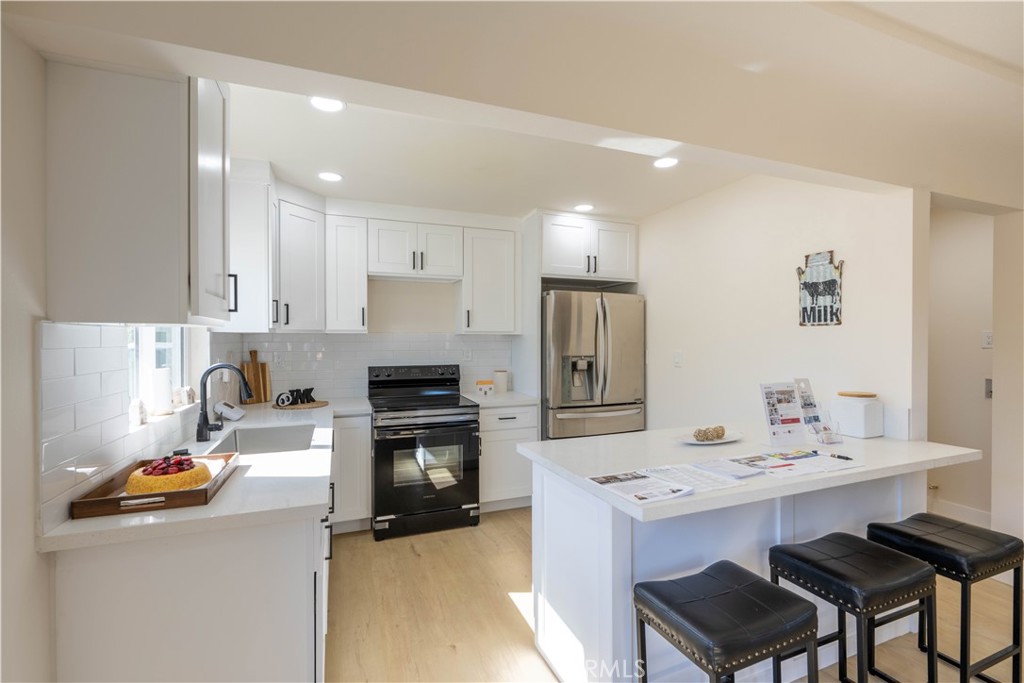 911 West George Street Banning, CA 92220 - Photo 13 of 32 a kitchen with a sink a stove a refrigerator and chairs