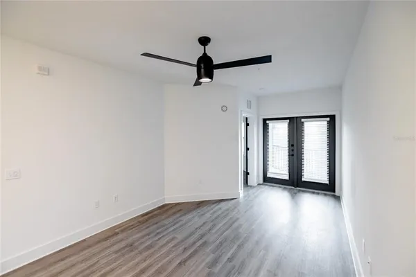 a view of an empty room with wooden floor and a window