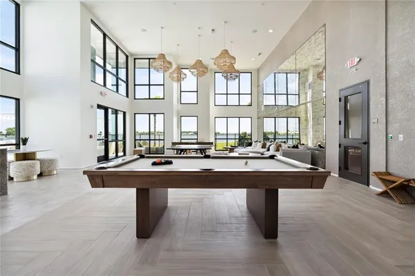 a dining hall with couches and potted plants with wooden floor