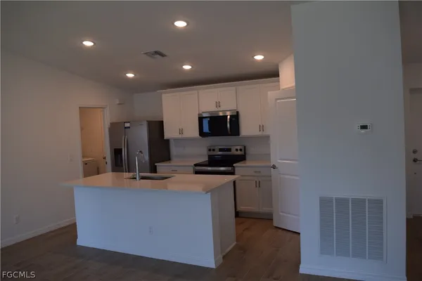a kitchen with kitchen island white cabinets and stainless steel appliances