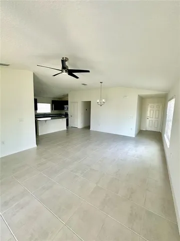 an empty room with windows and ceiling fan