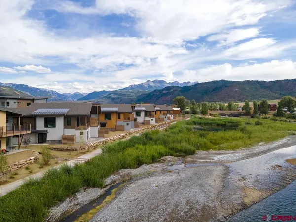 an aerial view of residential houses with outdoor space and trees