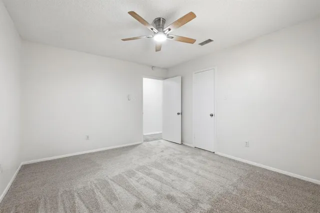 an empty room with a window and a fan