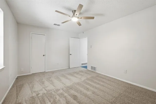 an empty room with windows and ceiling fan