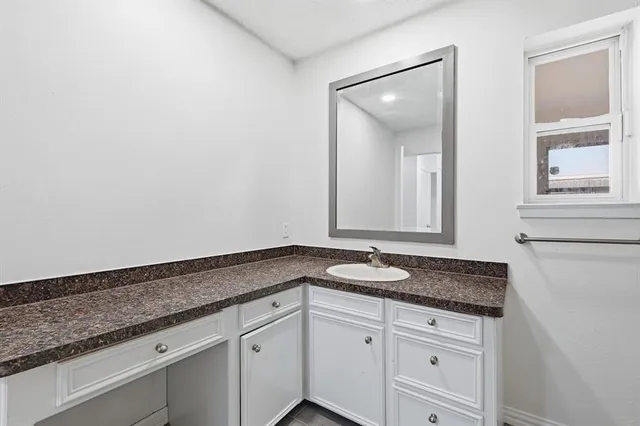a bathroom with a granite countertop sink a mirror and a window