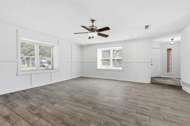 an empty room with windows and ceiling fan