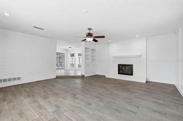 a view of an empty room with wooden floor and a fireplace