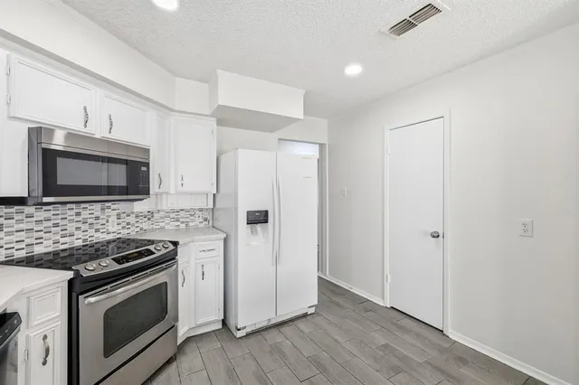 a kitchen with stainless steel appliances white cabinets and wooden floor
