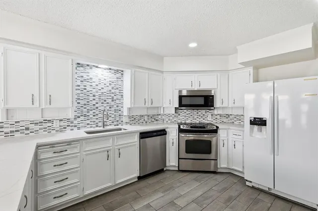 a kitchen with stainless steel appliances white cabinets and a stove top oven