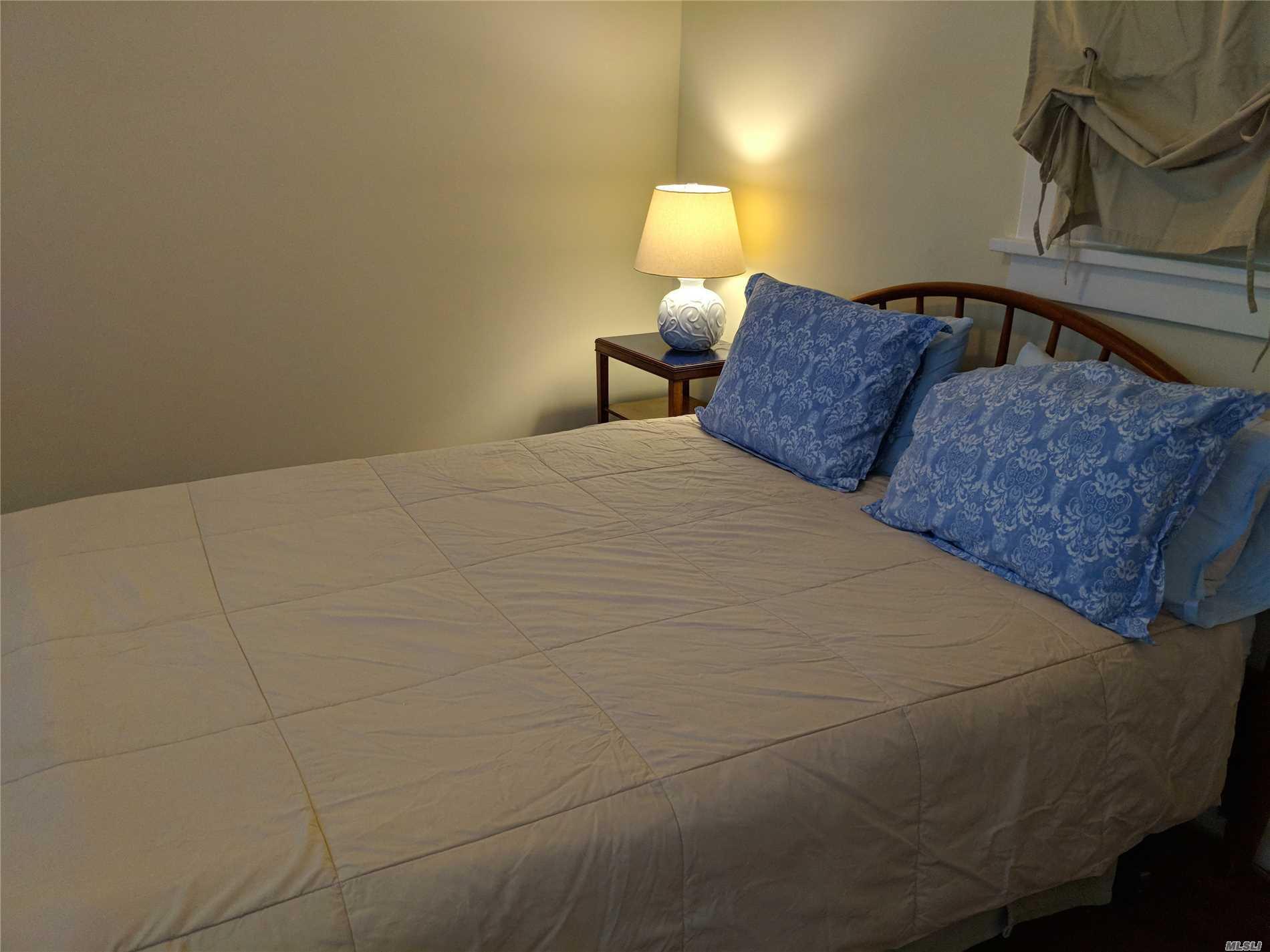 16640 Main Street, Unit COTTAG New Suffolk, NY 11956 - Photo 8 of 11 a bedroom with a bed and lamp with window