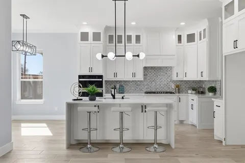 a kitchen with white cabinets and window