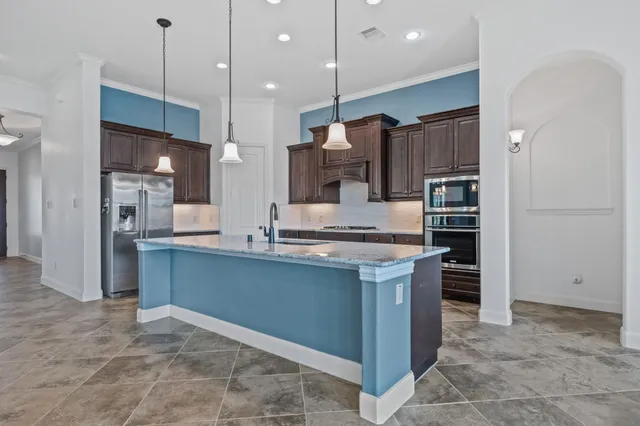 a kitchen with stainless steel appliances kitchen island granite countertop a refrigerator and a sink