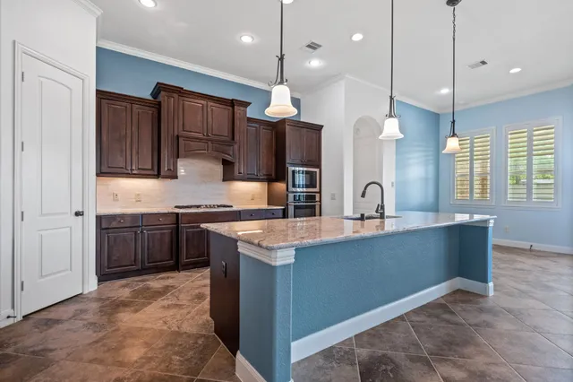 a kitchen with stainless steel appliances granite countertop a sink a stove and a wooden floor
