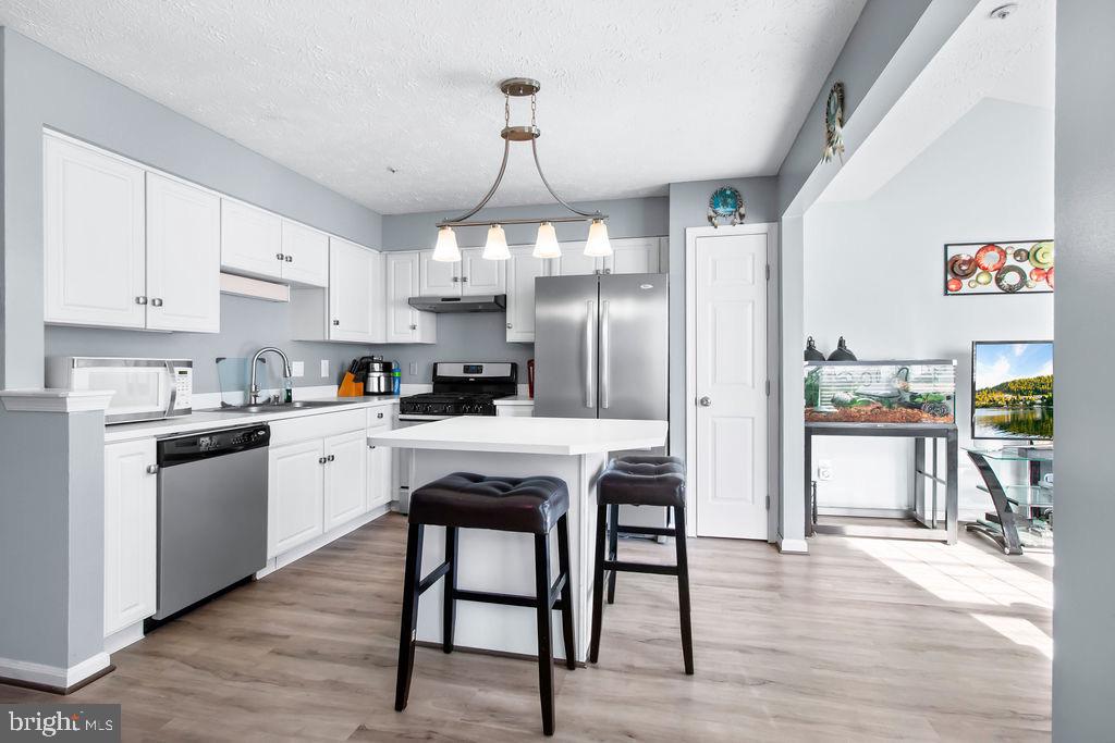 8605 Accokeek Street Laurel, MD 20724 - Photo 17 of 44 a kitchen with granite countertop a refrigerator a stove a sink dishwasher a dining table and chairs with wooden floor