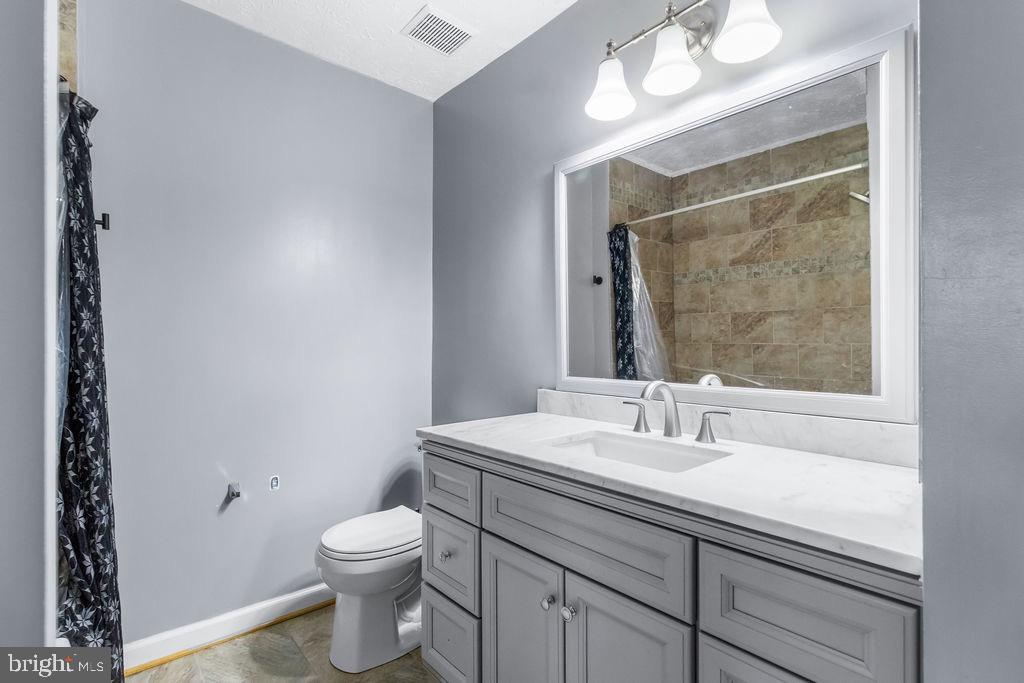 8605 Accokeek Street Laurel, MD 20724 - Photo 24 of 44 a bathroom with a toilet a sink a mirror and a shower