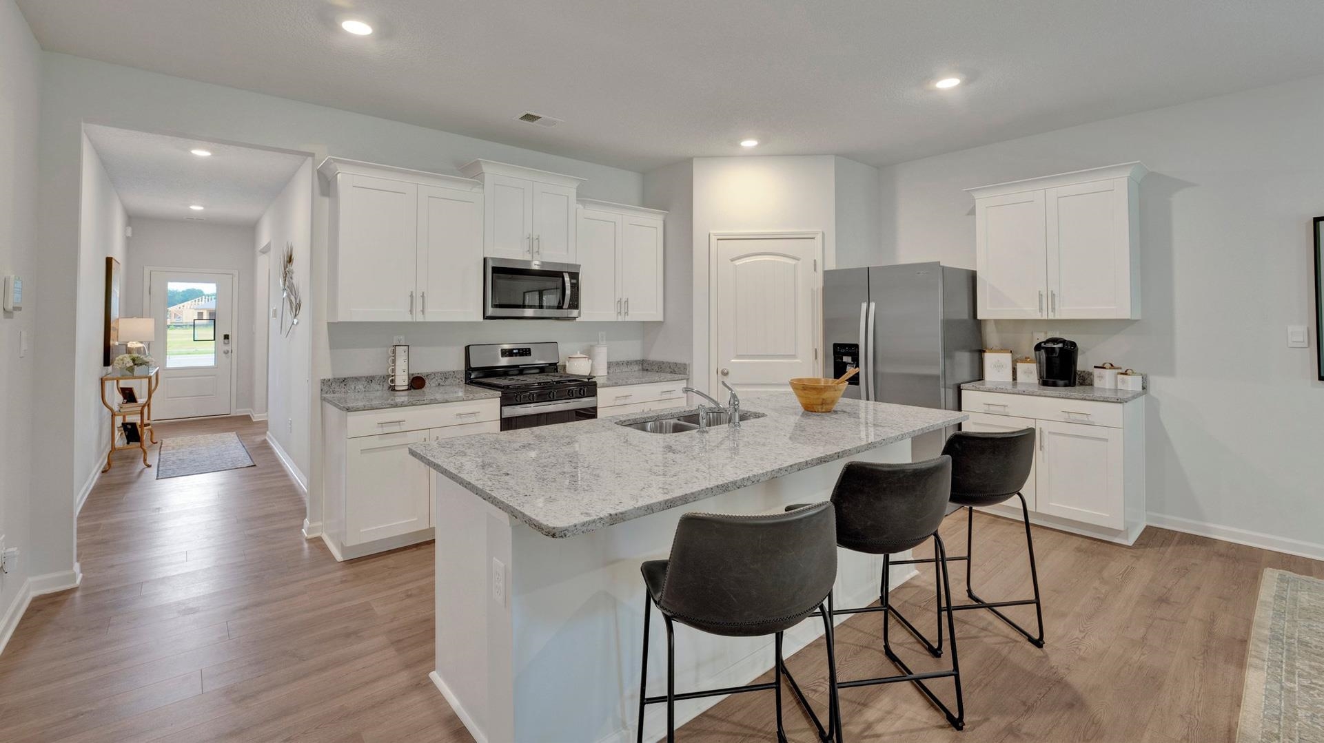 345 Windemere Loop Oakland, TN 38060 - Photo 10 of 23 a kitchen with stainless steel appliances kitchen island granite countertop a stove a sink a refrigerator and a dining table with wooden floor