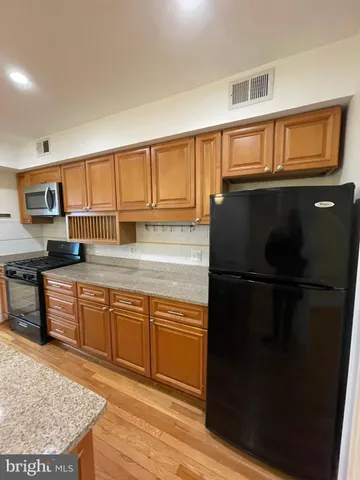 a kitchen with granite countertop a refrigerator stove top oven and sink