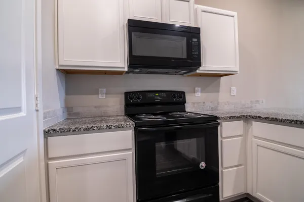 a kitchen with stainless steel appliances granite countertop white cabinets and a stove top oven
