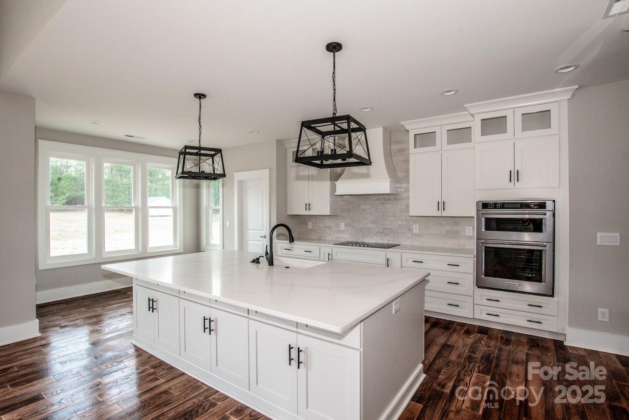 6098 Ballard Road Denver, NC 28037 - Photo 22 of 48 a kitchen with stainless steel appliances a sink stove and wooden floor