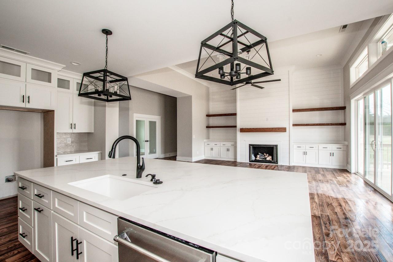 6098 Ballard Road Denver, NC 28037 - Photo 23 of 48 a kitchen with a sink a chandelier stainless steel appliances and a chandelier