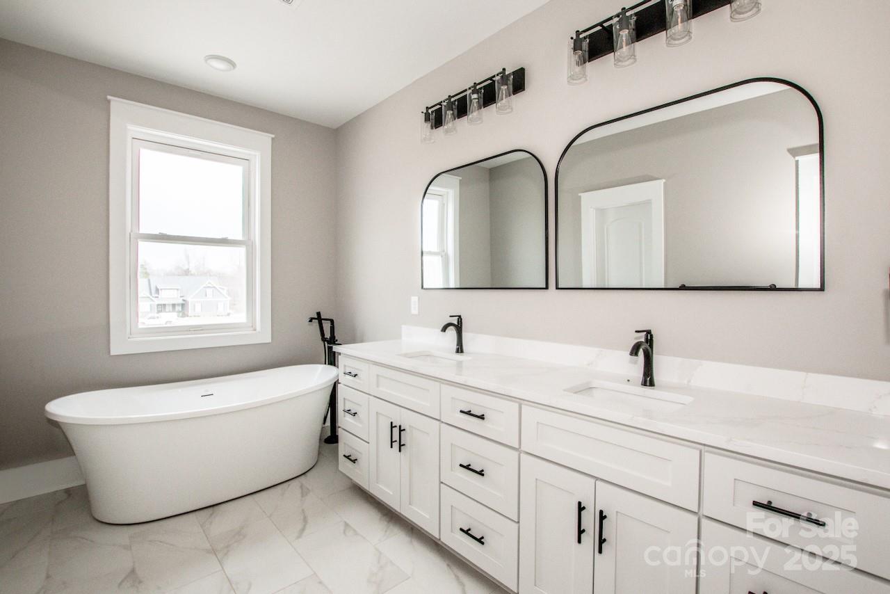6098 Ballard Road Denver, NC 28037 - Photo 32 of 48 a bathroom with a double vanity sink bathtub and window
