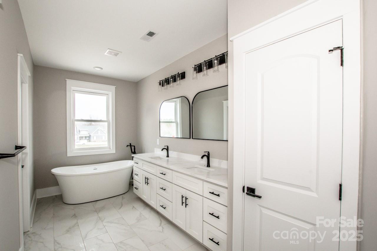 6098 Ballard Road Denver, NC 28037 - Photo 33 of 48 a spacious bathroom with a double vanity sink a mirror and a bathtub
