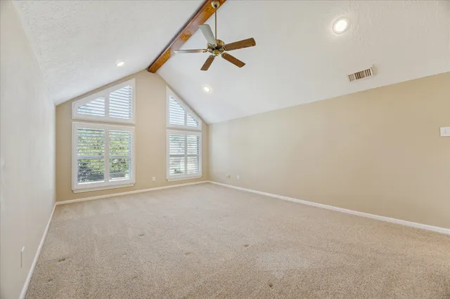 an empty room with windows and ceiling fan