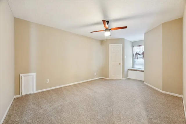 a view of an empty room and chandelier fan