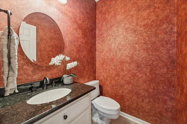 a bathroom with a granite countertop sink mirror vanity and toilet