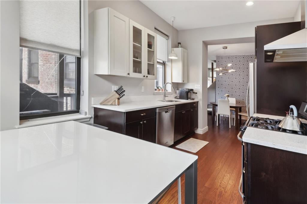 5259 Carnegie Street Lawrenceville, PA 15201 - Photo 16 of 50 a kitchen with a sink and a stove top oven with wooden floor
