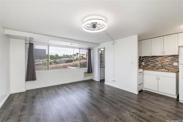 an empty room with wooden floor cabinet and windows