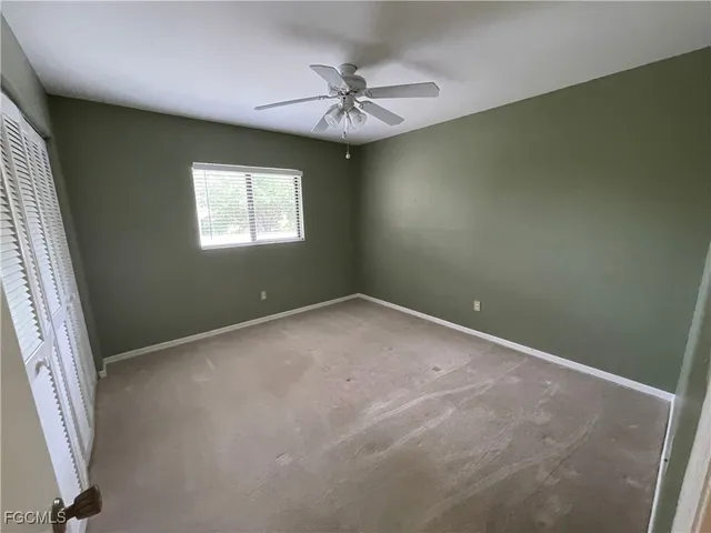 an empty room with a ceiling fan and window