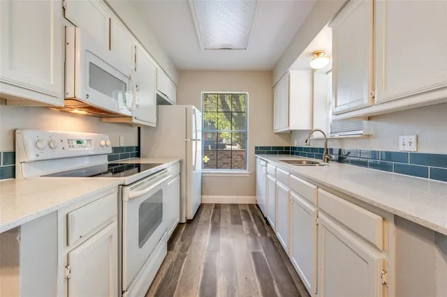 a kitchen with granite countertop a sink stainless steel appliances and white cabinets