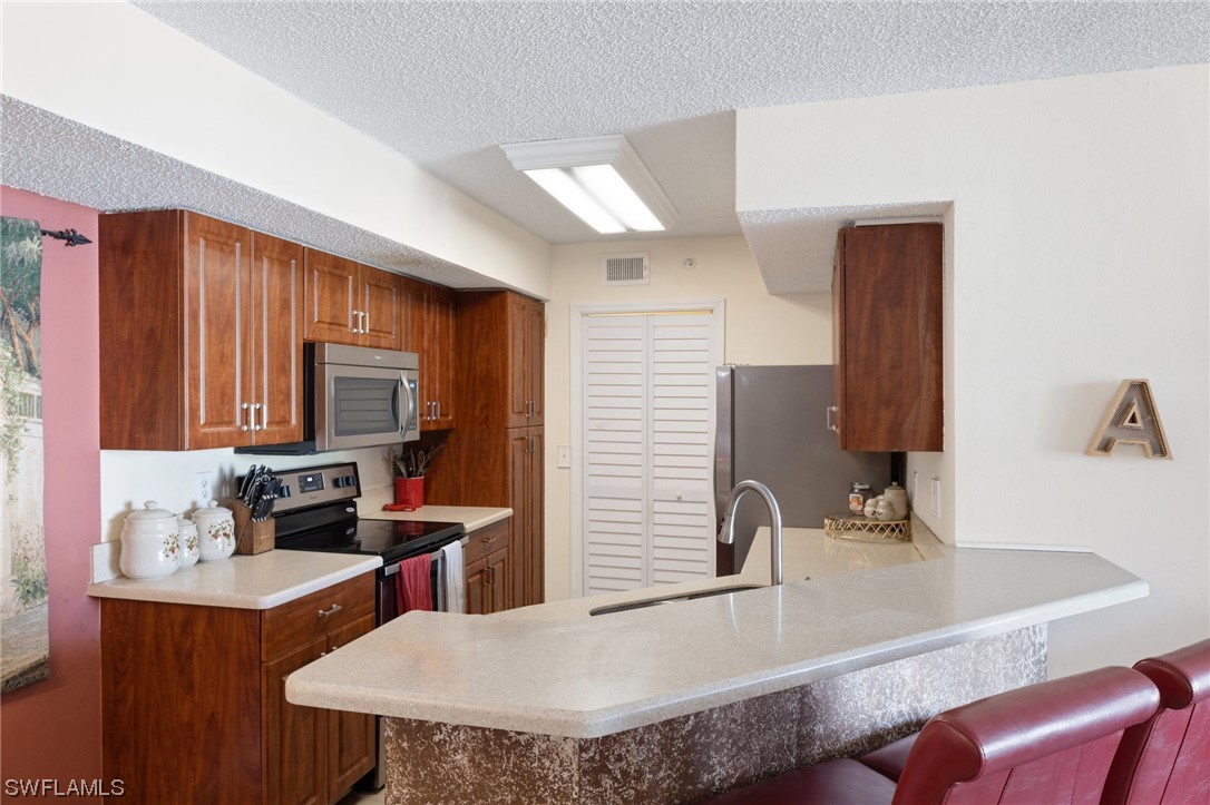 13571 Eagle Ridge Drive, Unit 1325 Fort Myers, FL 33912 - Photo 4 of 26 a kitchen with granite countertop a sink and a refrigerator
