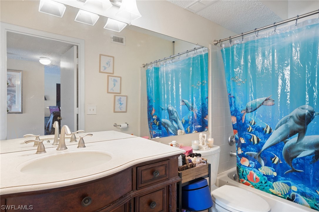 13571 Eagle Ridge Drive, Unit 1325 Fort Myers, FL 33912 - Photo 7 of 26 a bathroom with a sink a toilet and shower curtain