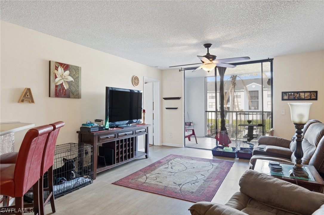 13571 Eagle Ridge Drive, Unit 1325 Fort Myers, FL 33912 - Photo 9 of 26 a living room with furniture a flat screen tv and a large window