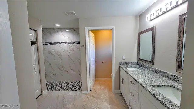 a spacious bathroom with a granite countertop sink mirror and shower