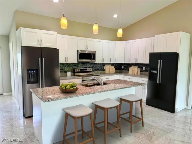 a kitchen with stainless steel appliances a dining table chairs refrigerator and microwave