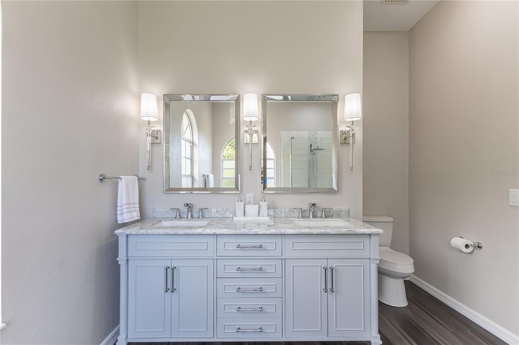 12230 Padron Boulevard Spring Hill, FL 34609 - Photo 12 of 22 a bathroom with a granite countertop double vanity sink a mirror and a toilet